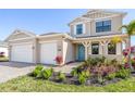 Charming two-story home featuring a welcoming blue door, two-car garage, and lush landscaping at 2563 Ocean Breeze Ln, Clearwater, FL 33761