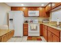 Traditional kitchen with wooden cabinetry, white appliances, tile flooring, and a granite countertop at 2595 Countryside Blvd # 8205, Clearwater, FL 33761