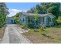 Charming single-story home featuring a front porch and a detached garage with a long driveway at 6709 N 13Th St, Tampa, FL 33604