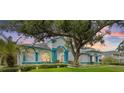 Stunning exterior of a home with blue trim, lush landscaping, and mature trees providing shade and curb appeal at 7314 Hunt Club Ln, Seminole, FL 33776