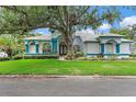 Charming home with blue trim and mature trees, showcasing its well-maintained lawn and inviting facade at 7314 Hunt Club Ln, Seminole, FL 33776