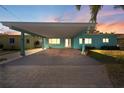 Charming home featuring a spacious carport and a brick driveway at sunset at 1025 Boca Ciega Isle Dr, St Pete Beach, FL 33706