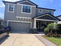 Charming two-story home with a gray stucco exterior, a two car garage, and a well manicured front lawn at 11219 Paddock Manor Ave, Riverview, FL 33569