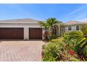Beautiful single-story home showcasing lush landscaping and a brick driveway leading to a three-car garage at 11910 Keating Dr, Tampa, FL 33626