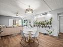 Bright living room featuring wood-look floors, stylish light fixture, and a wall of healthy plants at 129 Cypress Ct, Oldsmar, FL 34677