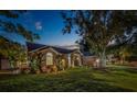 Twilight view of a well-manicured lawn with lovely landscaping and exterior lighting at 14073 Jennifer Ter, Largo, FL 33774
