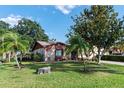 Lovely front yard with mature trees, lush green grass and a charming facade at 1823 Atrium Dr, Sun City Center, FL 33573