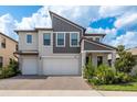 Two-story home featuring a paved driveway leading to a two-car garage, landscaped yard, and modern architectural details at 21590 Violet Periwinkle Dr, Land O Lakes, FL 34637