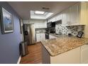 Bright kitchen features granite counters, white cabinets, tile backsplash, stainless steel appliances, and a skylight at 404 Lennox W Rd # 404, Palm Harbor, FL 34683