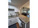Kitchen view features granite counters, white cabinets, stainless steel appliances, and view into the living room at 404 Lennox W Rd # 404, Palm Harbor, FL 34683