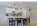Bright kitchen features stainless steel appliances, large kitchen island with counter seating and pendant lighting at 4730 Wandering Way, Wesley Chapel, FL 33544