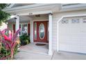 Close-up of the front door with sidelights, house number, and landscaping at 6216 Evansbrook Dr, Zephyrhills, FL 33541