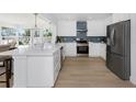 Modern kitchen with white cabinets, stainless steel appliances, and a blue backsplash design at 6321 Balboa Ln, Apollo Beach, FL 33572