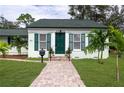 Close-up of the front entrance, highlighting the green door, manicured lawn, and charming brick pathway at 701 38Th N Ave, St Petersburg, FL 33704