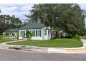 Corner lot home with a green roof, white siding, lush lawn, and mature landscaping showcasing its curb appeal at 701 38Th N Ave, St Petersburg, FL 33704