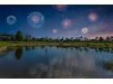 Scenic pond reflecting fireworks and a colorful sunset, surrounded by lush green spaces at 8717 Emeraldwood Way, Land O Lakes, FL 34637