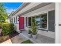 Inviting entryway features a vibrant pink door, gray shutters, and stylish potted plants on the front porch at 1124 35Th Ne Ave, St Petersburg, FL 33704