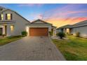 Single-story home with a well-manicured lawn and a brick-paved driveway at sunset at 11819 Brighton Knoll Loop, Riverview, FL 33579