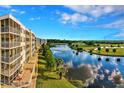 Exterior view of condo buildings with screened balconies overlooking lush golf course and lake at 1200 Country Club Dr # 5506, Largo, FL 33771
