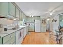 Bright kitchen with white appliances, light green cabinets, and wood laminate flooring at 123 Saint Kitts Way, Apollo Beach, FL 33572