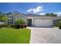 Beautiful single-story home with a two car garage, complemented by a lush lawn and elegant paver driveway at 13013 Satin Lily Dr, Riverview, FL 33579