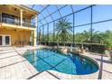 Beautiful screened-in pool area with a water feature, lush landscaping, and covered lanai at 2101 N Pointe Alexis Dr, Tarpon Springs, FL 34689