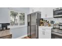 Kitchen with stainless steel refrigerator, white cabinets, marble backsplash, window, and wood-look floors at 2211 Belleair Rd # D3, Clearwater, FL 33764