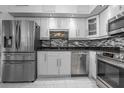 Modern kitchen featuring stainless steel appliances, mosaic backsplash, white cabinets and tile floors at 30 Turner St # 202, Clearwater, FL 33756