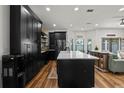 Modern kitchen with black cabinets, a large island, stainless steel appliances, and hardwood floors at 3221 W Oakellar Ave, Tampa, FL 33611