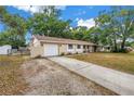 Side view of the home featuring a gravel driveway, one-car garage, and a quaint covered porch with a swing at 3753 Hollow Oak Pl, Land O Lakes, FL 34639