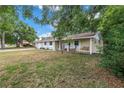Inviting home exterior with a covered porch, complete with rocking chairs and a swing, framed by mature trees and a lawn at 3753 Hollow Oak Pl, Land O Lakes, FL 34639