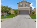 Two-story home with a two-car garage, neutral paint, minimalist landscaping, and shutters on the upper windows at 5068 Little Stream Ln, Wesley Chapel, FL 33545