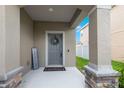 Inviting front porch with stone accents, a gray front door with wreath, and a welcome mat at 5068 Little Stream Ln, Wesley Chapel, FL 33545