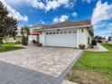 View of the two-car garage and a brick-paved driveway at 9253 Water Hazard Dr, Hudson, FL 34667