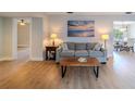 A stylish living room featuring wood-look flooring, a comfortable gray couch, and natural light at 1211 64Th Nw St, Bradenton, FL 34209