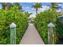 Inviting wooden walkway leads to a private dock, surrounded by lush greenery and a glimpse of the house at 1326 Apollo Beach S Blvd, Apollo Beach, FL 33572