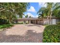 Beautiful one-story home with brick driveway, mature trees, and a three-car garage at 16 Hibiscus Rd, Belleair, FL 33756