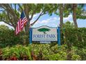 Forest Park Condominium Association community sign with an American flag, surrounded by lush greenery at 2170 Elm St # 906, Dunedin, FL 34698