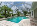 Inviting screened-in pool with travertine deck, lush landscaping, and ample space for entertaining at 23420 Peachland Blvd, Port Charlotte, FL 33954