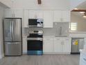 Charming kitchen features white cabinets, stainless steel appliances, tile backsplash, and wood-look flooring at 2728 58Th S St, Gulfport, FL 33707