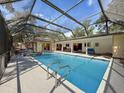 Screened-in pool featuring a sparkling swimming pool, covered seating area, and attached spa at 44 Pinewood Cir, Safety Harbor, FL 34695