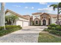 Beautifully landscaped home showcasing a three-car garage, brick driveway, red tile roof, and a mix of stone and siding accents at 5405 Tybee Island Dr, Apollo Beach, FL 33572