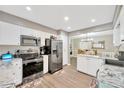 Bright kitchen featuring stainless steel appliances, white cabinets, and wood flooring at 607 Carolyn Dr, Brandon, FL 33510