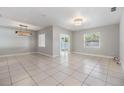 Bright living room with neutral tile flooring, a modern light fixture, and natural light at 7012 S Trask St, Tampa, FL 33616