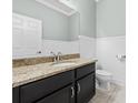 Half bath with granite countertop, dark cabinetry, and wainscoting at 7699 Windchase Way, Wesley Chapel, FL 33545
