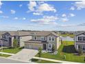 A neighborhood view showcasing a two-story home with a well manicured front yard with water feature in background at 9287 Crescent Ray Dr, Wesley Chapel, FL 33545