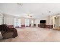 Bright living room features carpet, ceiling fan, and a large window for natural light at 11514 Sun Rd, Dade City, FL 33525
