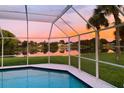 Screened-in pool offers stunning sunset views over the tranquil lake at 128 Torrington St, Port Charlotte, FL 33954
