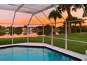Screened-in pool offers stunning sunset views over the tranquil lake at 128 Torrington St, Port Charlotte, FL 33954