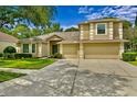 Inviting two-story home boasts a lush lawn, mature trees, and a spacious driveway leading to a three-car garage at 19207 Autumn Woods Ave, Tampa, FL 33647